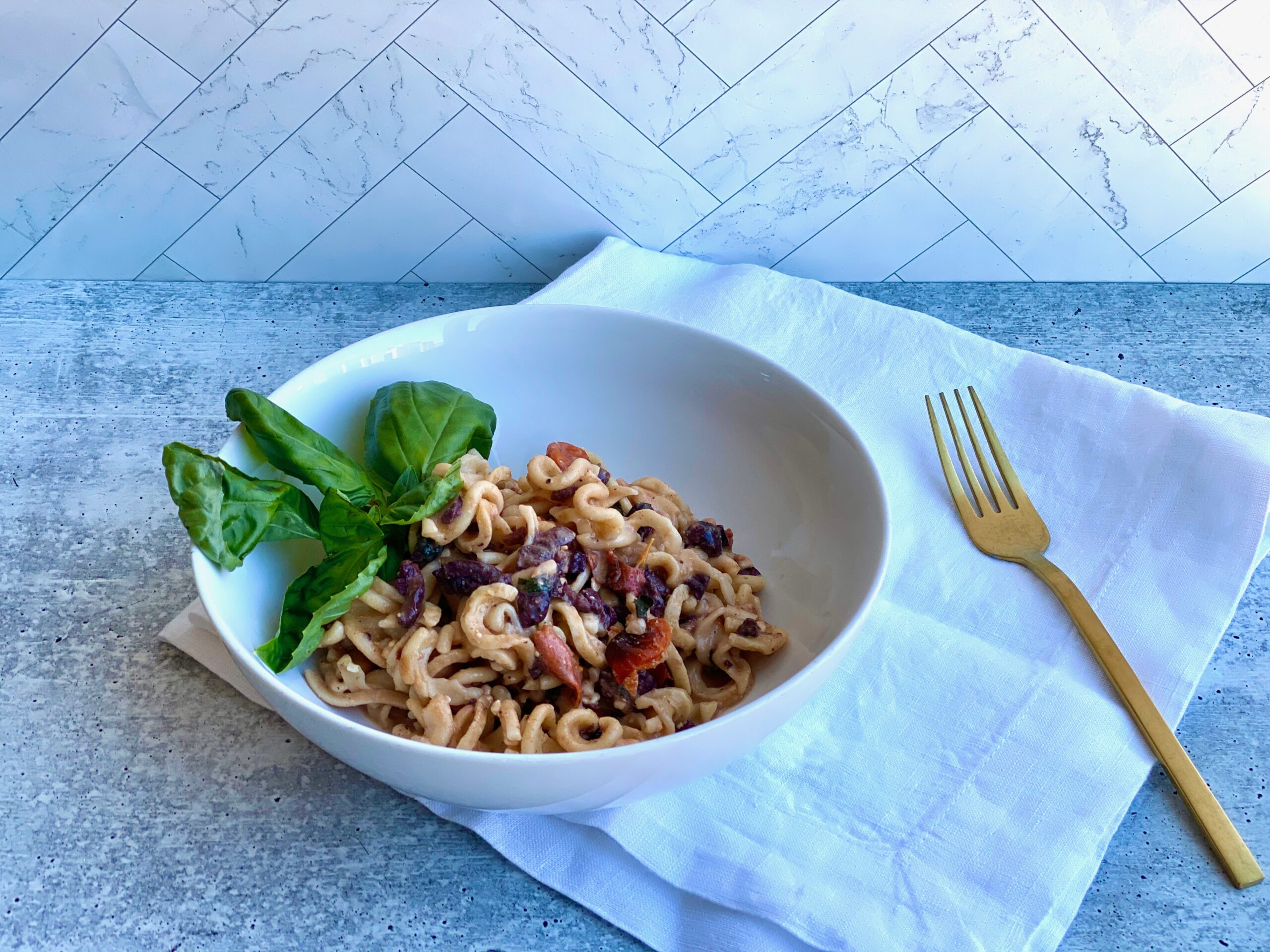 Image of a bowl of pasta with a fork and napkin next to it