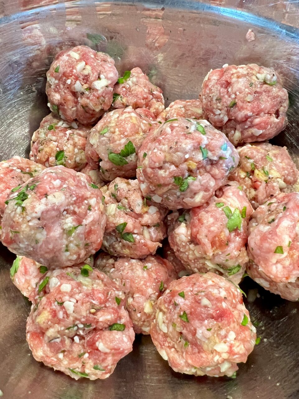 Meatballs with Tomato Cream Sauce A metal bowl filled with raw meatballs