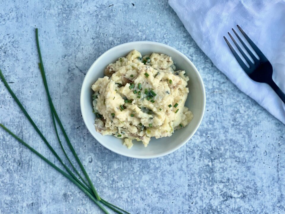 A bowl of smashed potatoes with green garlic