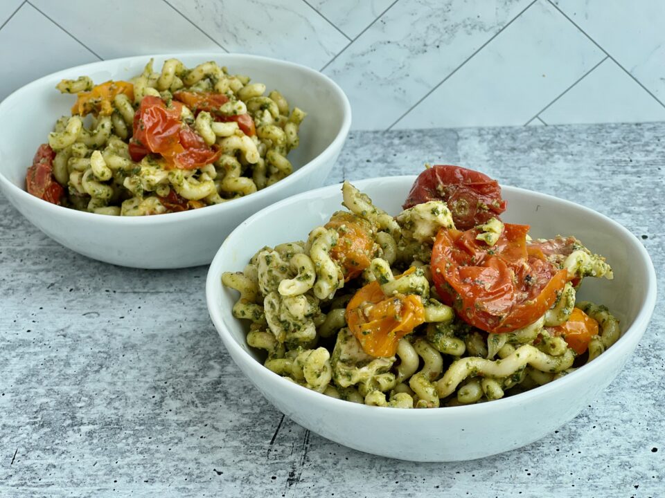 Easy Pesto Pasta with Roasted Tomatoes Two bowls of pesto pasta with roasted tomatoes in it