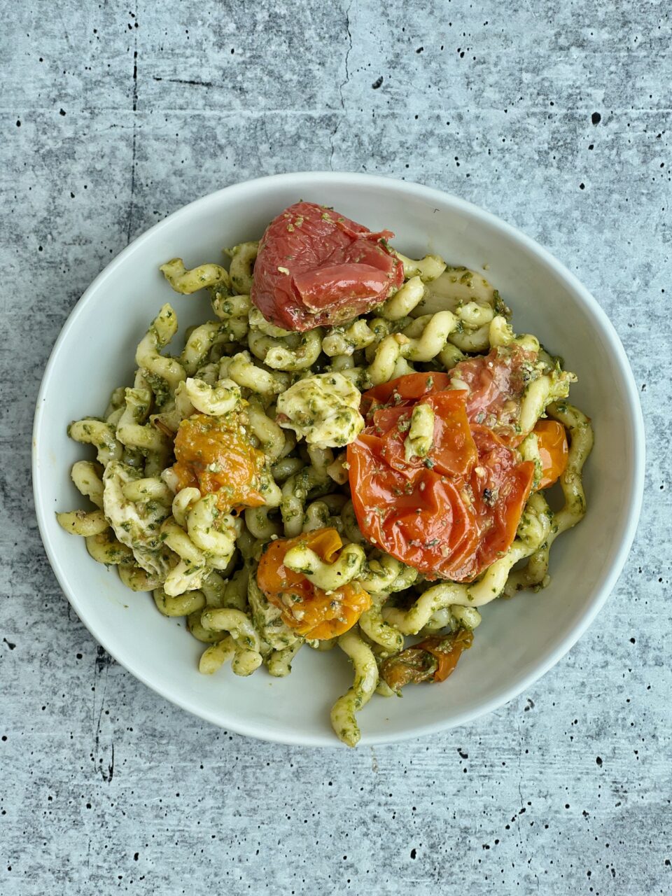Easy Pesto Pasta with Roasted Tomatoes A bowl of pesto pasta with roasted tomatoes in it