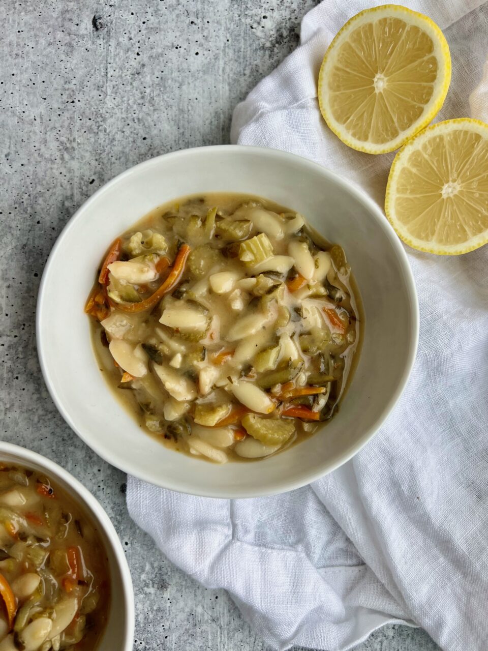 Creamy Lemon Orzo Soup A bowl of lemon orzo soup with lemons in the background