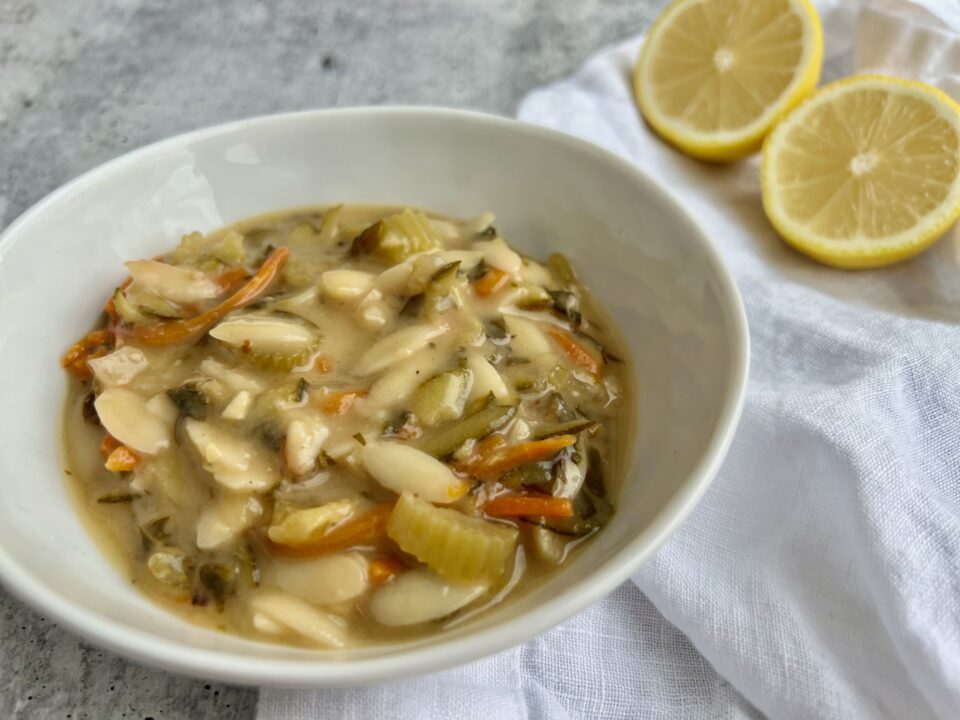Creamy Lemon Orzo Soup A bowl of lemon orzo soup with lemons in the background